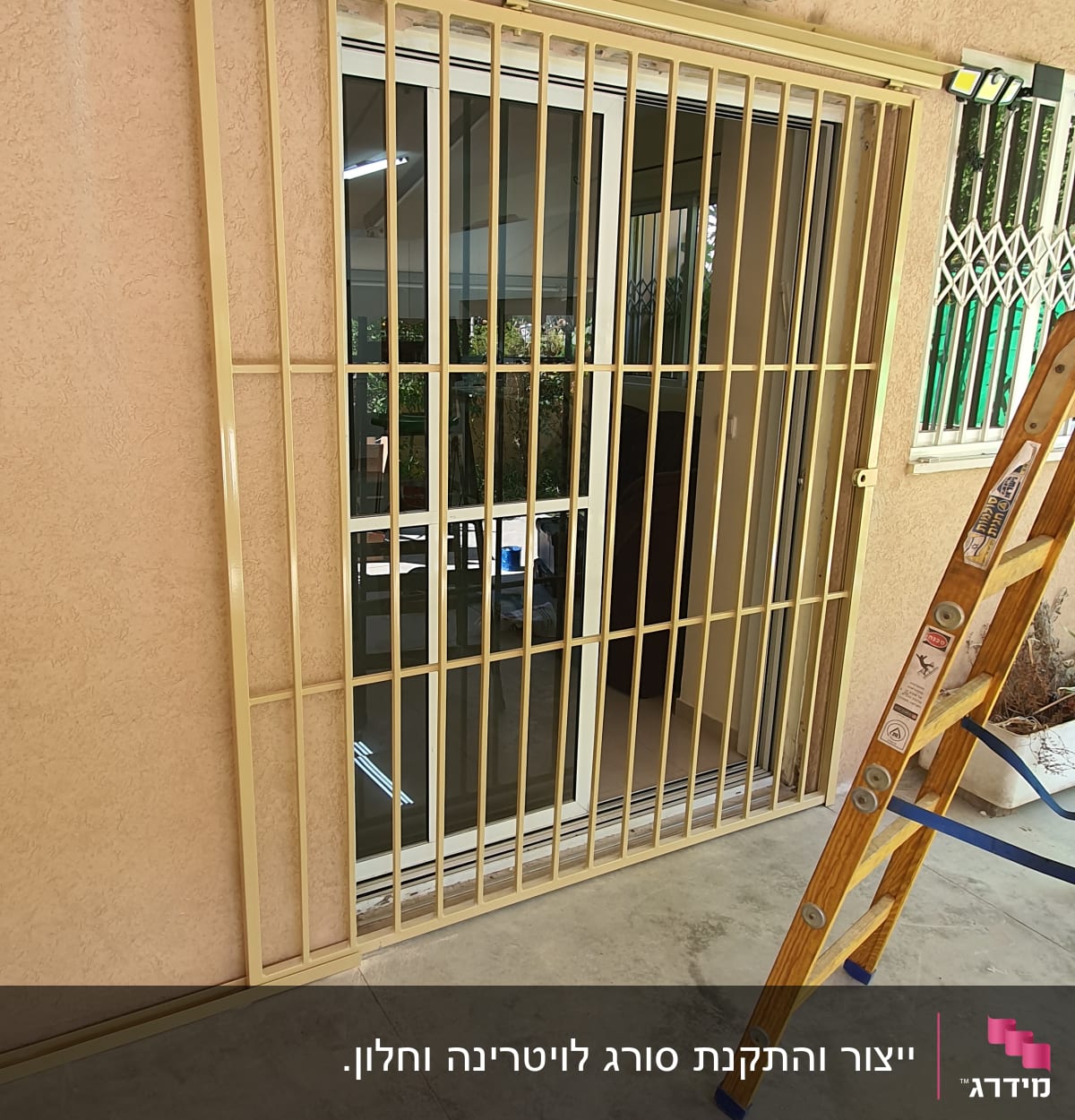סורג מתכת על חלון זכוכית עם סולם עץ בצד